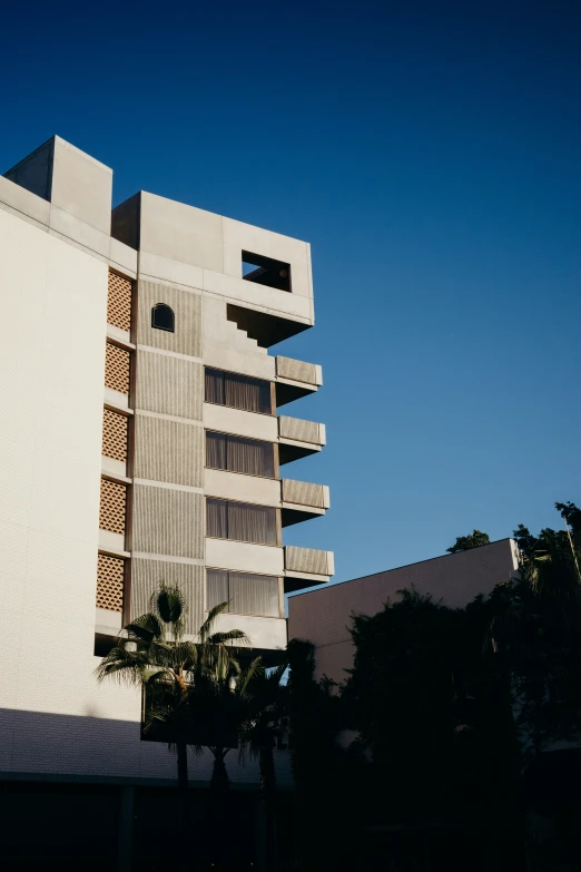 a white tall building sitting next to a tree