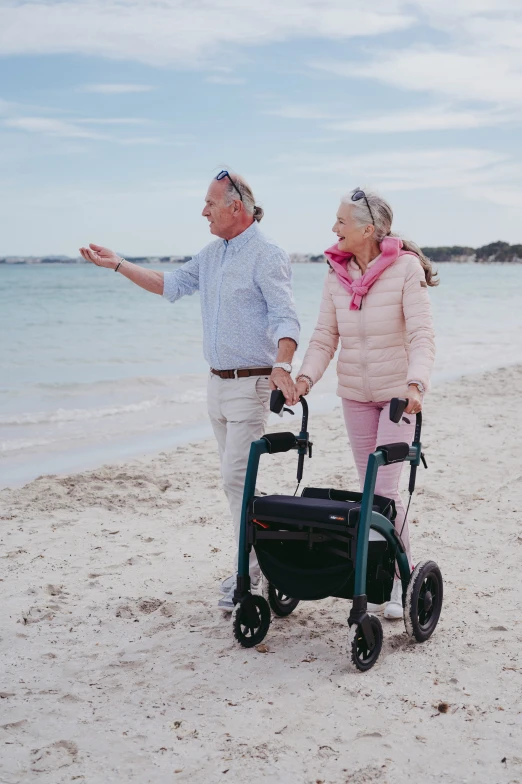 a man and woman walking on the beach with luggage