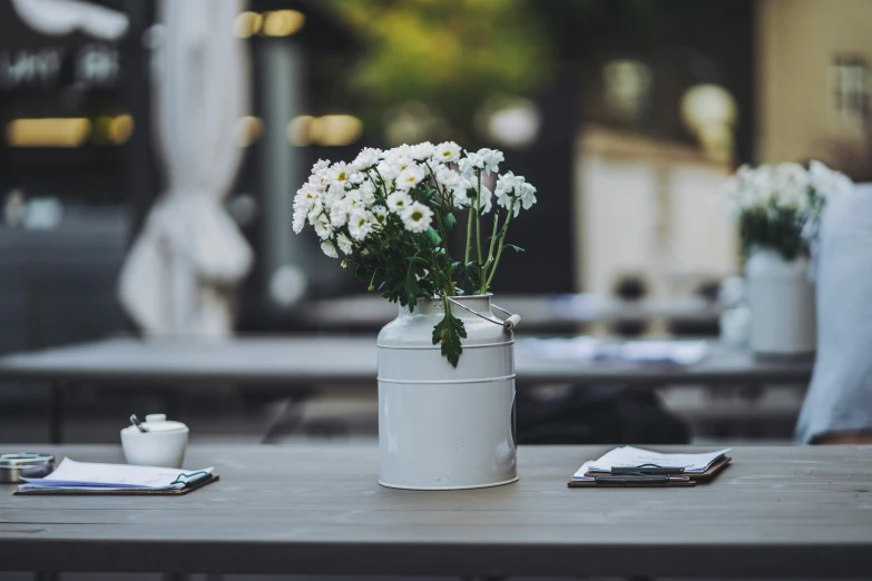 white flowers in an old can is arranged on a table