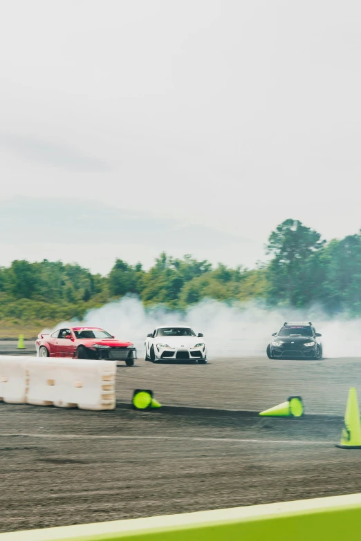 some cars are driving on an racetrack and the cars are about to burn