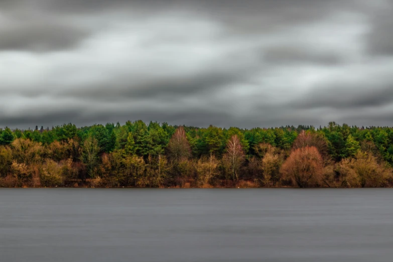 a boat is on the water as it sails in front of the green forest