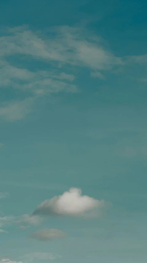 a single white cloud is in the middle of the blue sky