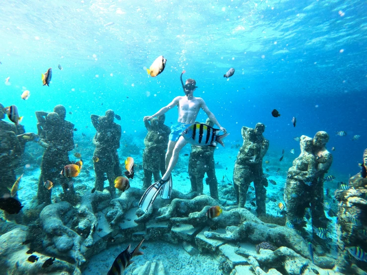 a man in black swimsuit standing on a rocky reef