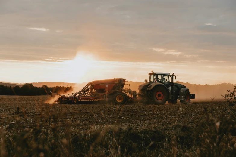 a tractor with two buckets is spraying grain into the field