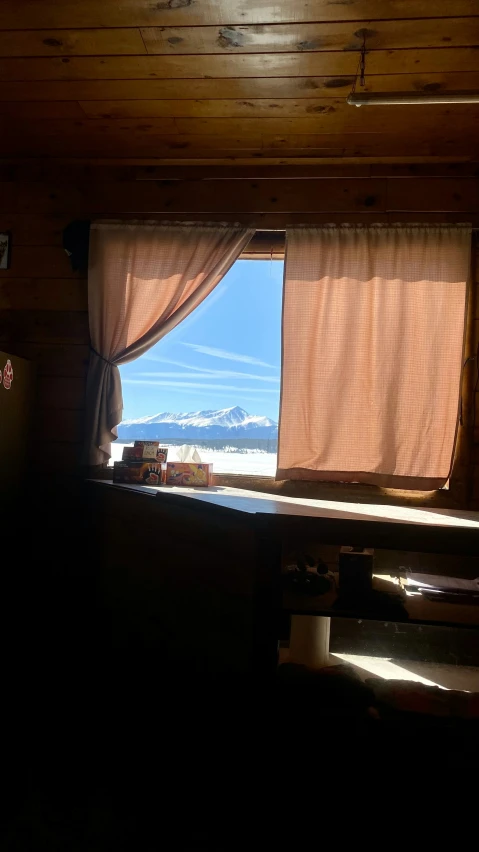 a small cabin window has a view of the mountain