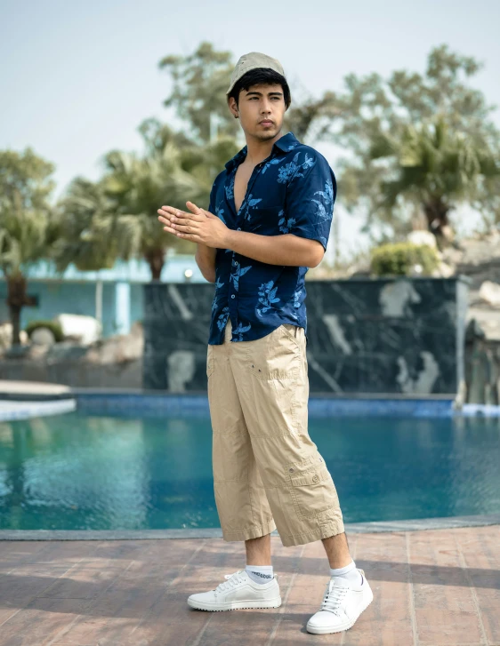 a man with sunglasses on standing next to a pool