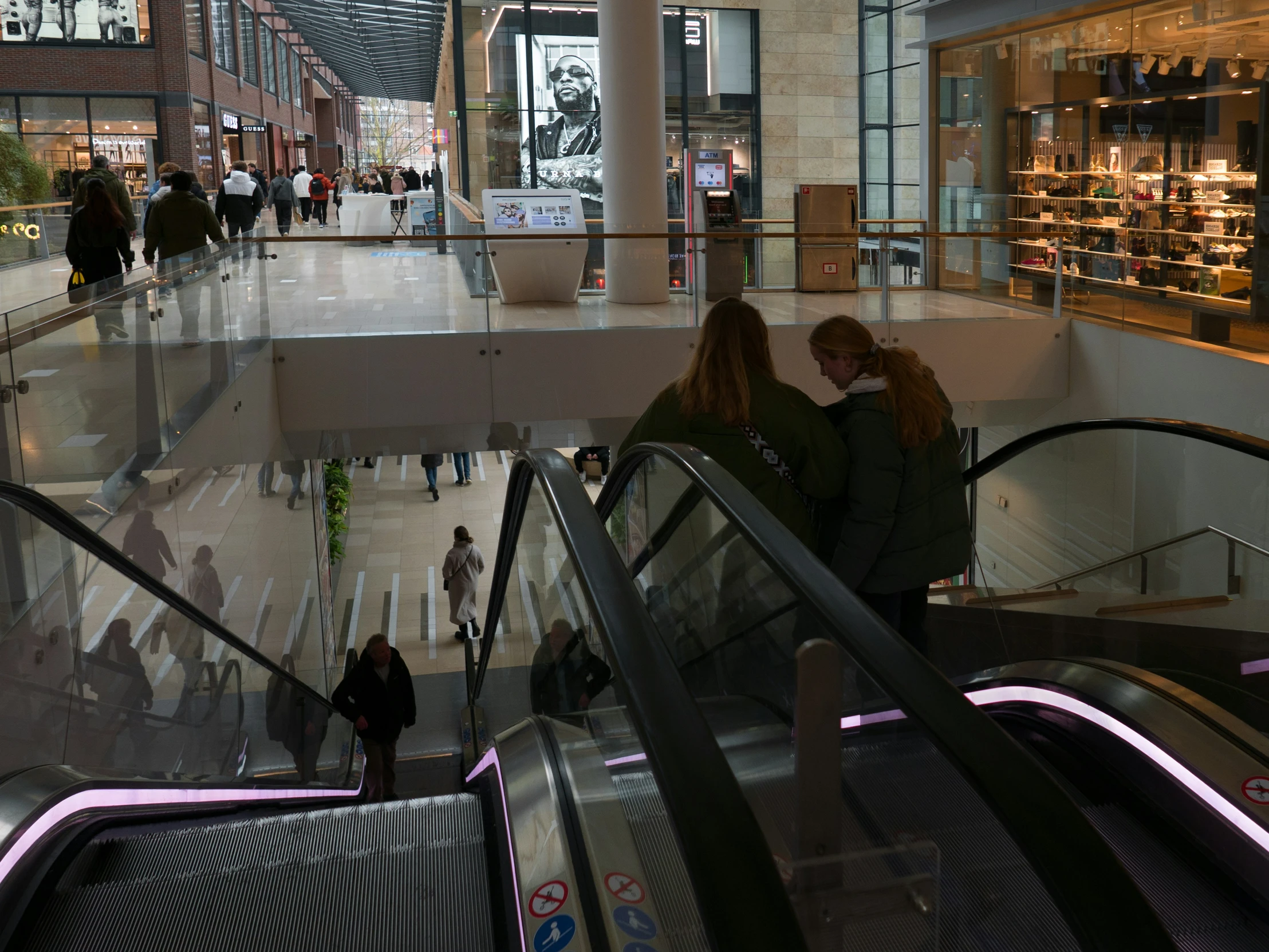 two people hugging on an escalator in a shopping mall