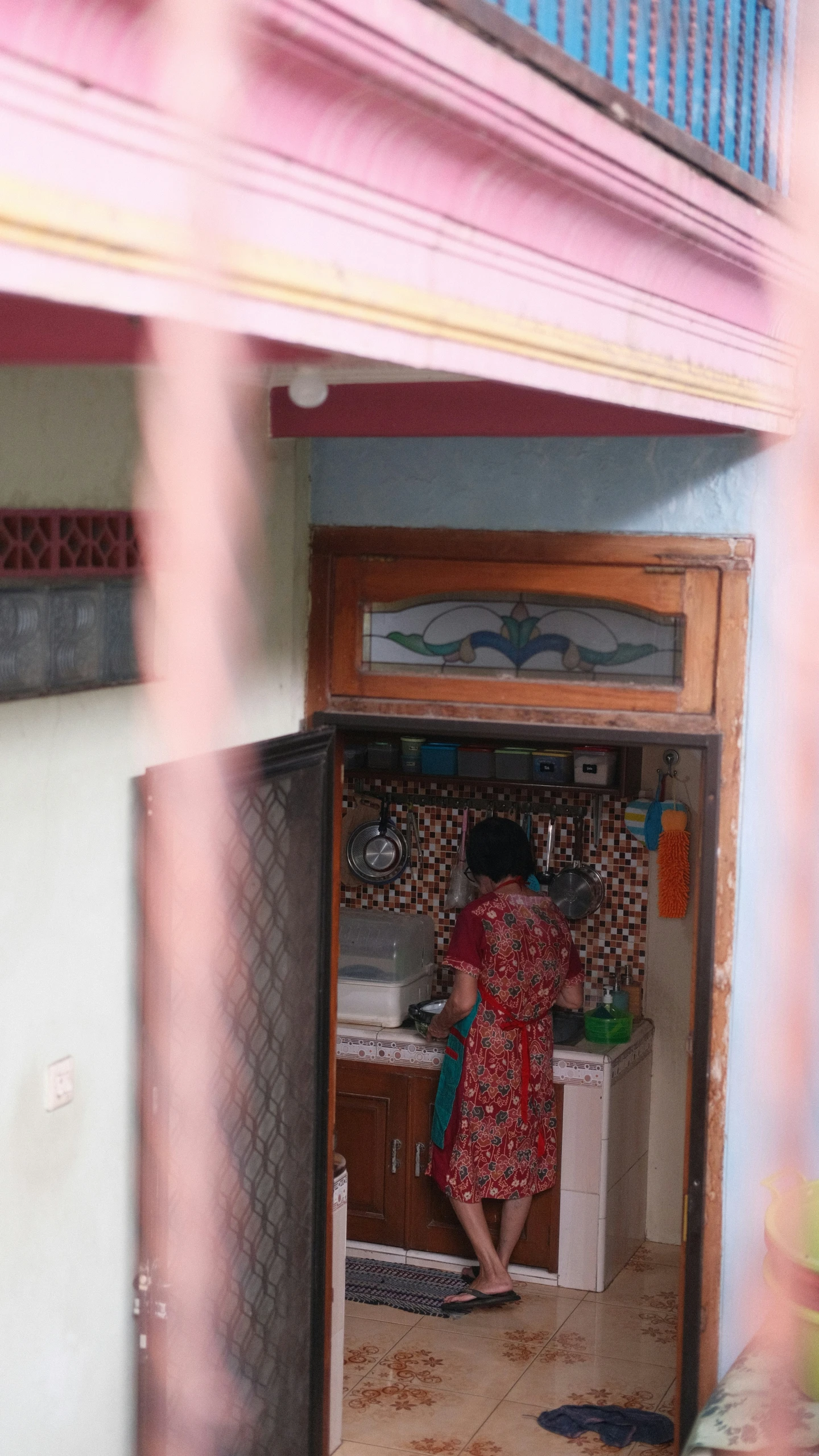 a woman in a red dress is making soing in a small kitchen