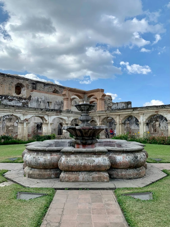 a large building with grass and a fountain in the center