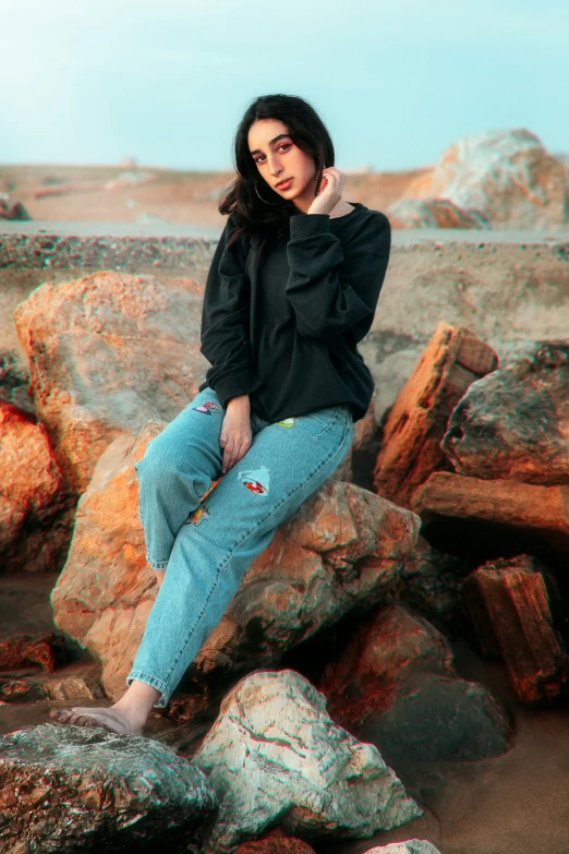 woman in black sweatshirt and jeans sitting on rocks