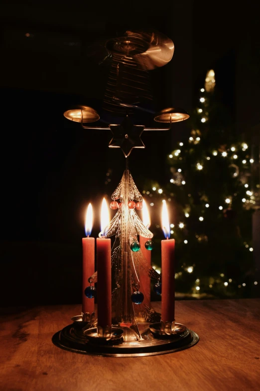 candles lit in a light arrangement in front of a christmas tree