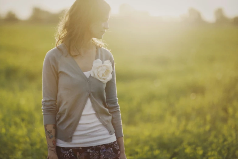 a woman in an open field in a cardigan