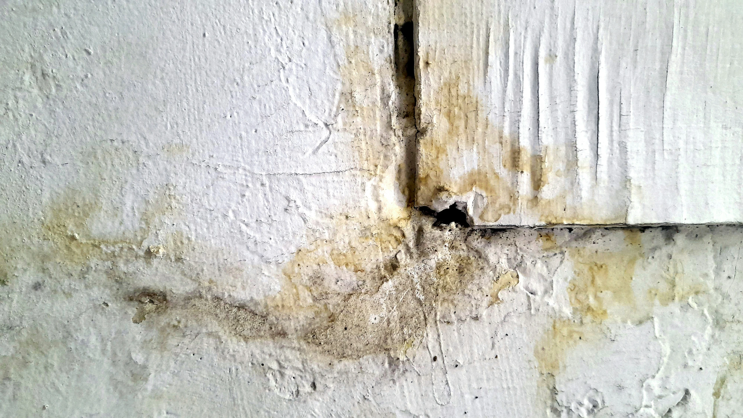 an old peeling plaster wall with some water spots and rust