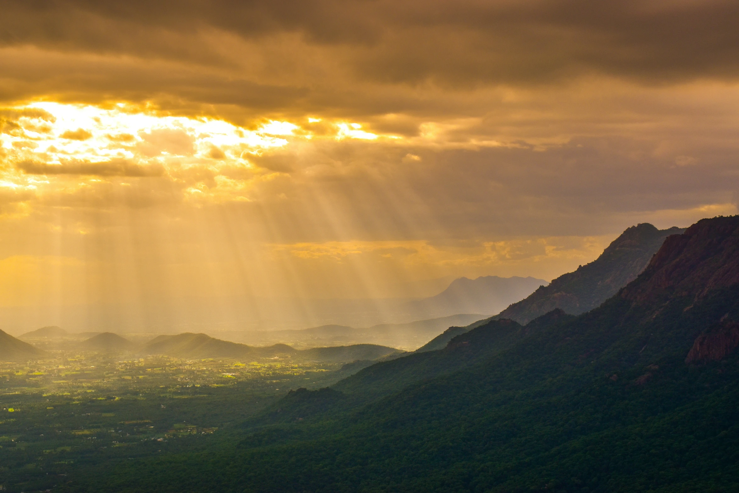 sunlight coming through clouds above mountains with light beams