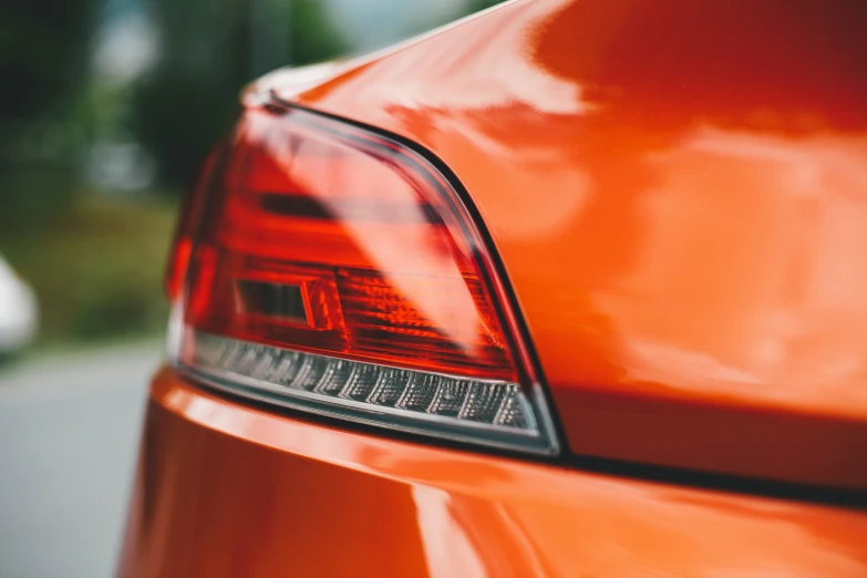orange tail light on orange car with trees in the background