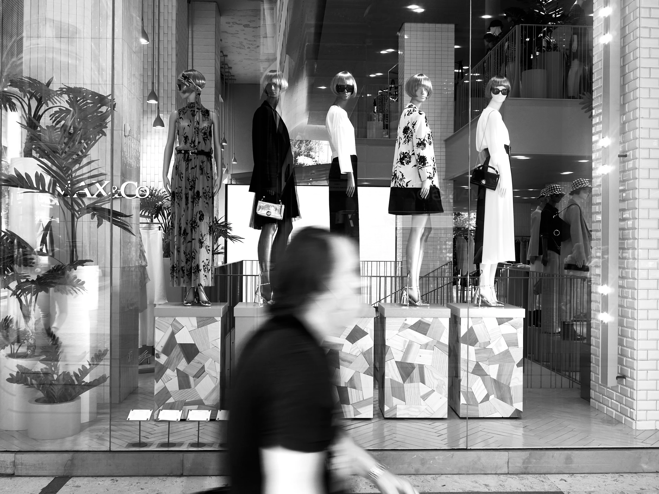 man walking past shop window with clothing and shopping items