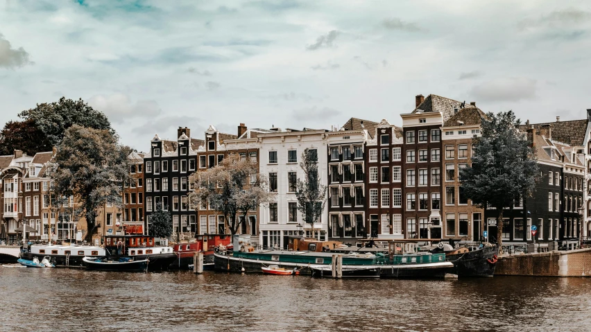 a river with a group of boats sitting next to buildings on the bank