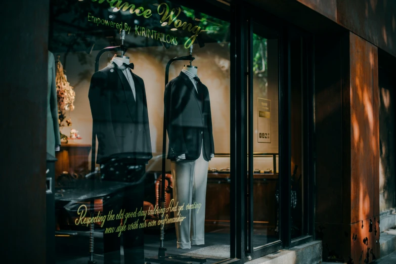 a store window displays two men's suits, one in a black suit