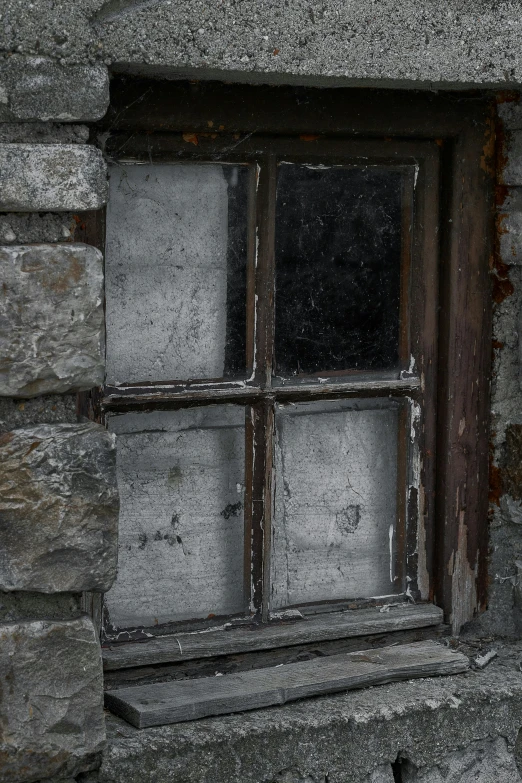 the window in the old stone wall is made out of wood