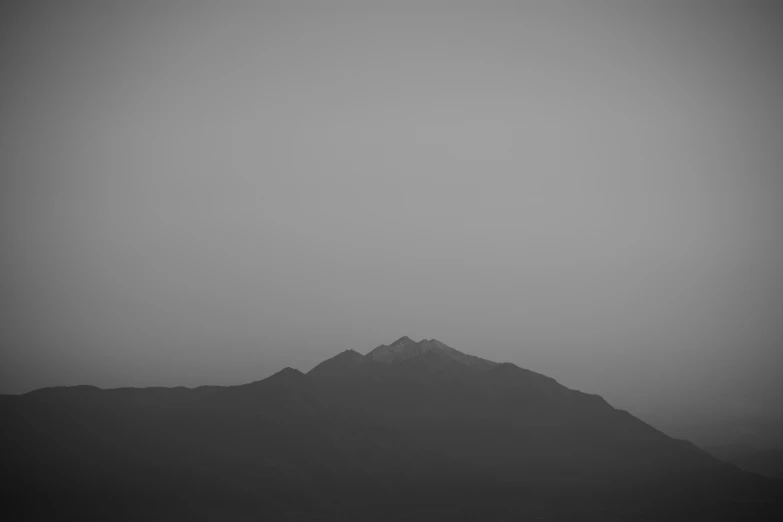a dark and hazy picture of mountains on a cloudy day