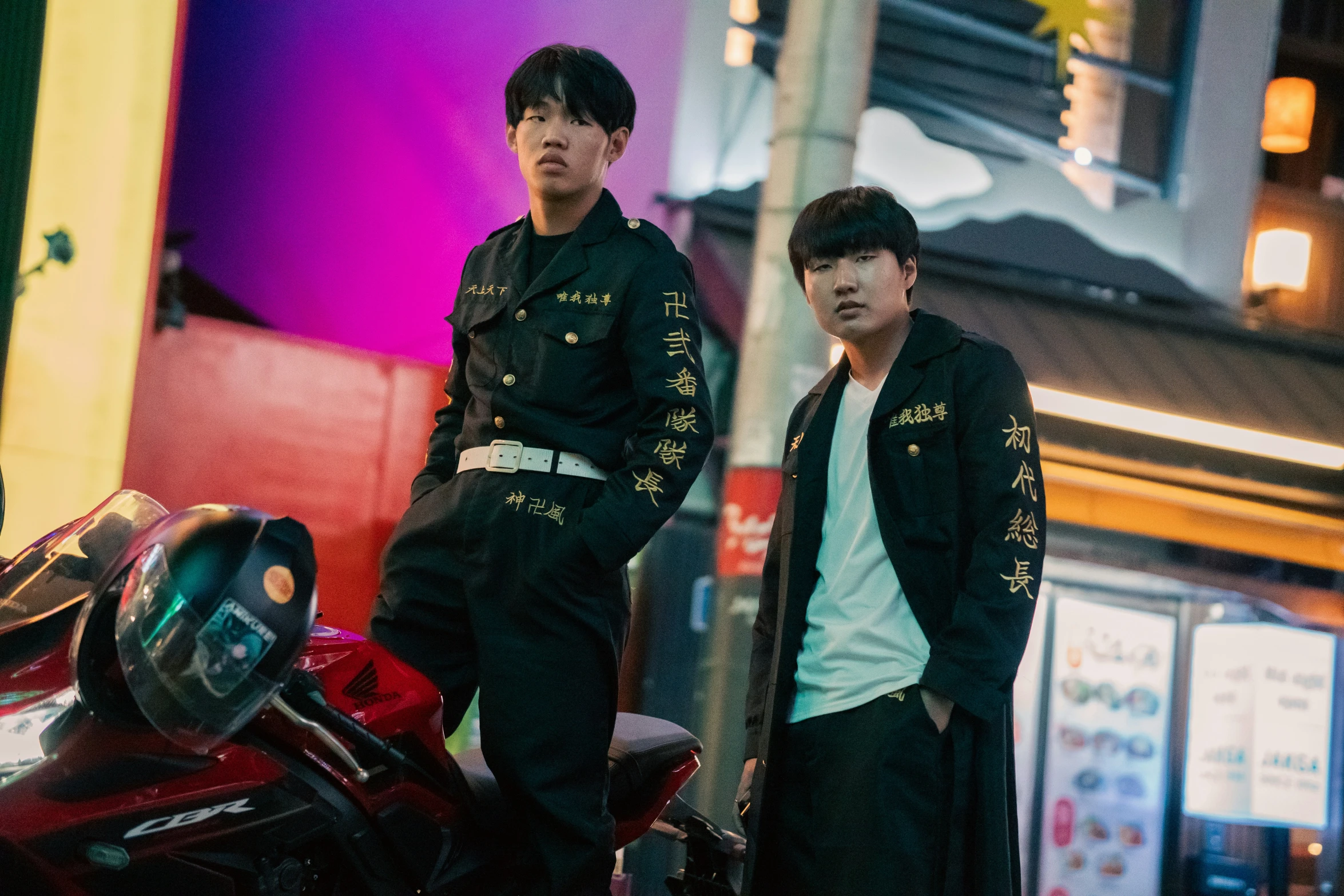 two men are standing near a parked motorcycle