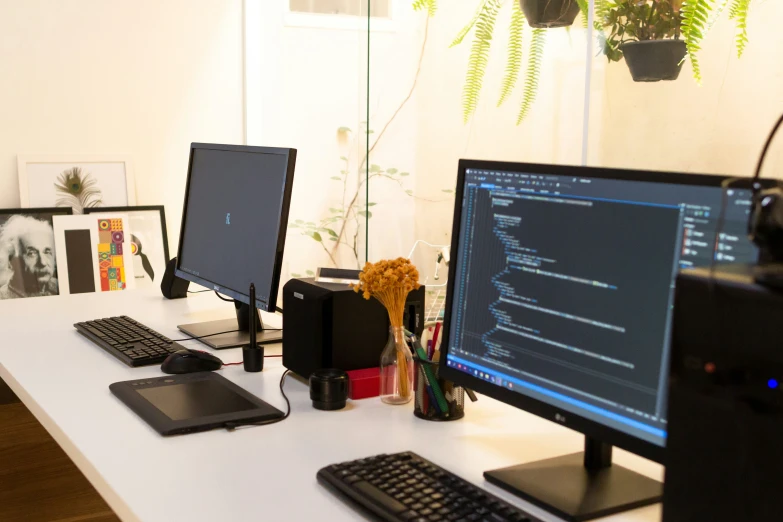 two computer monitors sit on a desk next to two keyboards and mouse