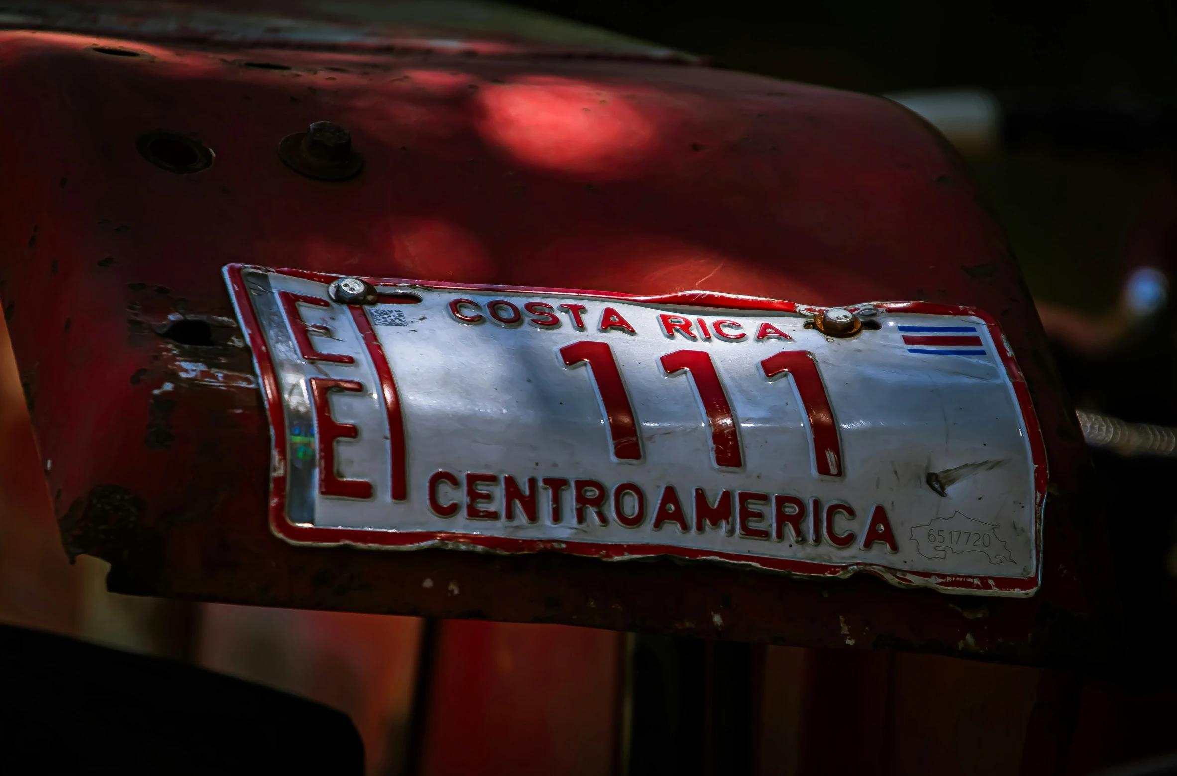 a license plate in spanish on the bumper of an old red car