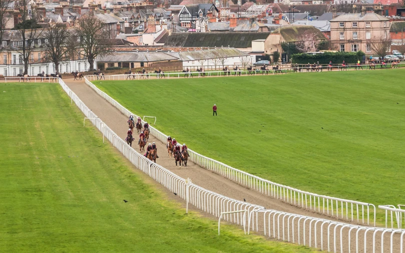 a group of people riding horses around a track