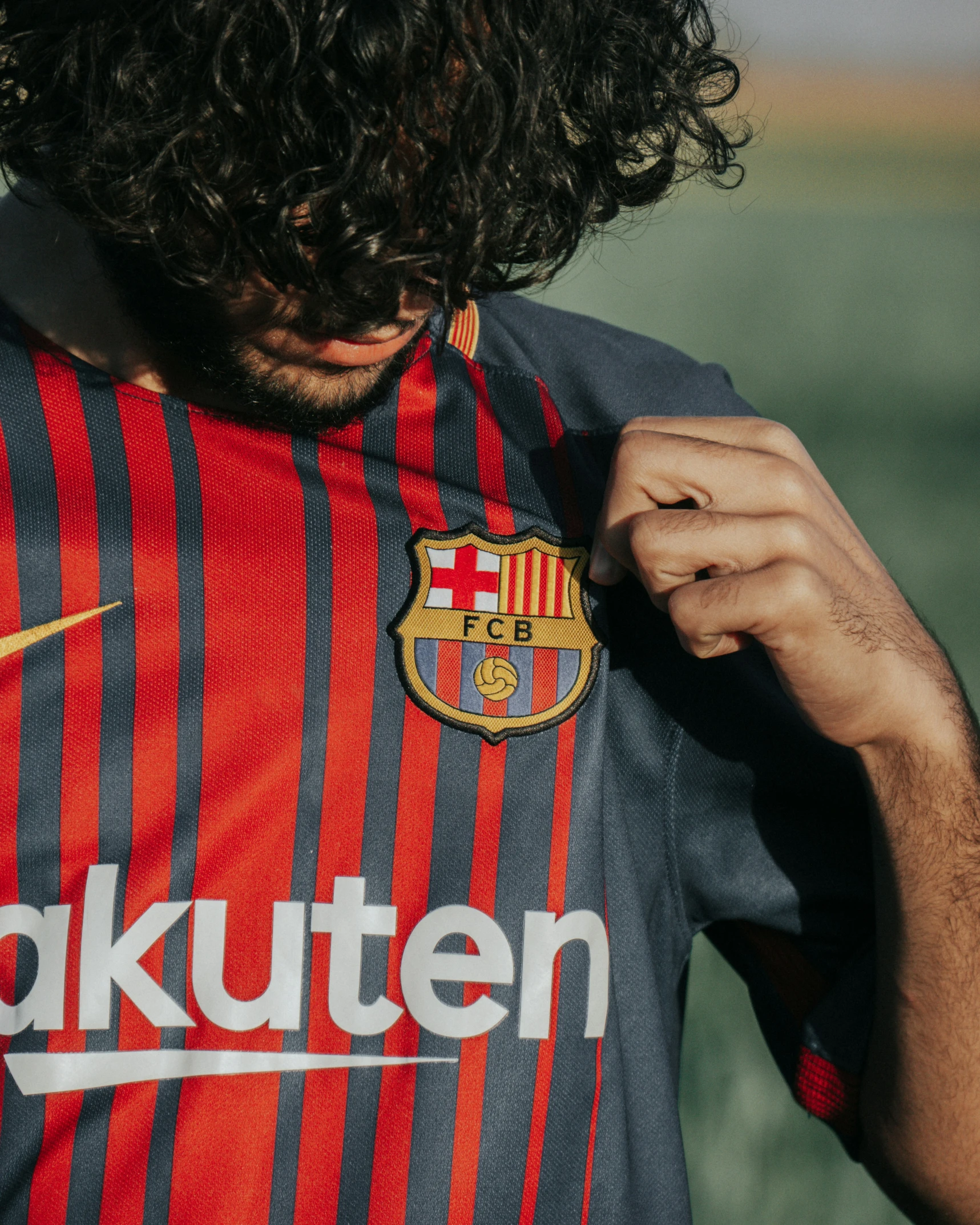 a man with curly hair adjusting his shirt