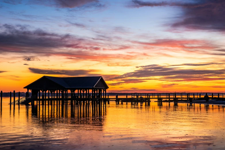 the sun is setting behind a dock and body of water