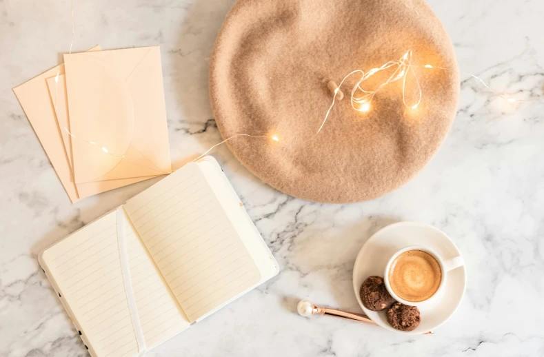 an open book, a cup of coffee, and some sort of writing equipment