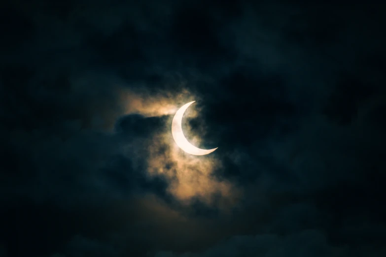 a crescent moon is seen during a cloudy night