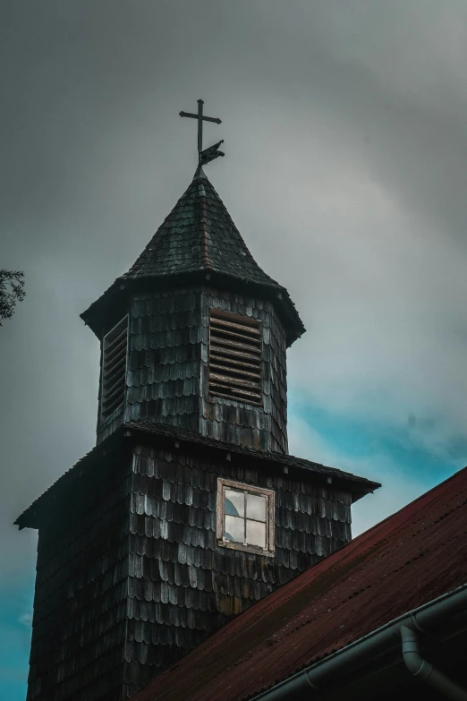 the dark weather looks over a roof and the steeple of a wooden church