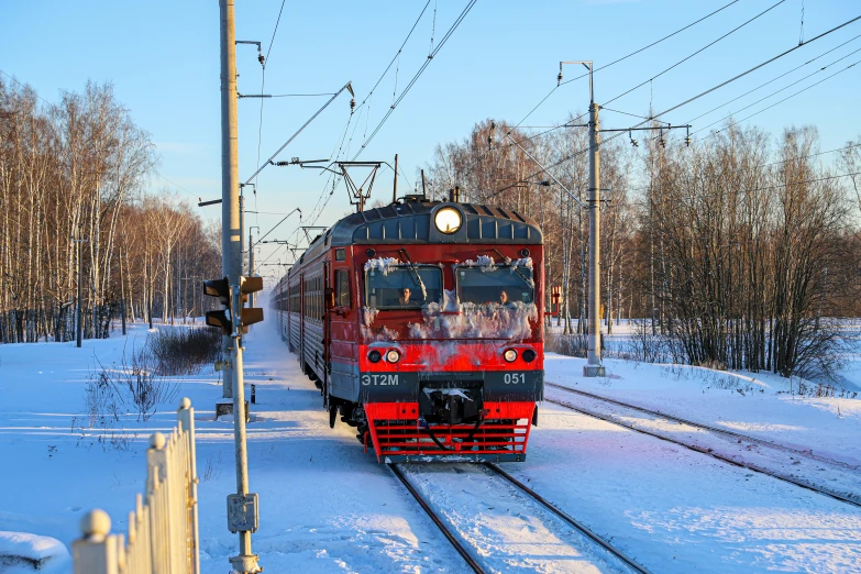 a red train passing by a snow covered path