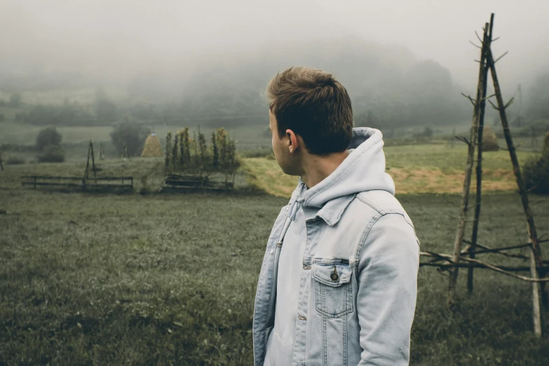 man standing alone in a field on a misty day