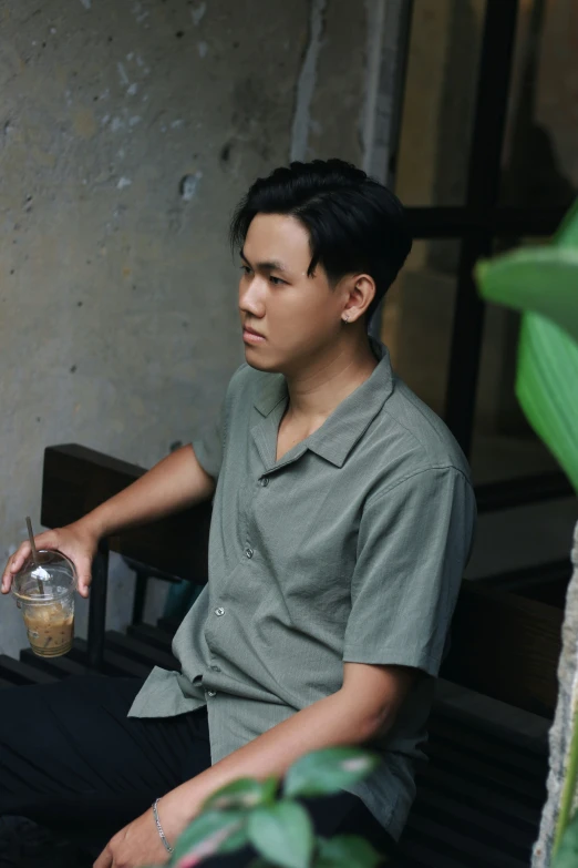 the boy is sitting down while holding a container