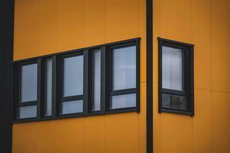an orange wall with windows next to a building