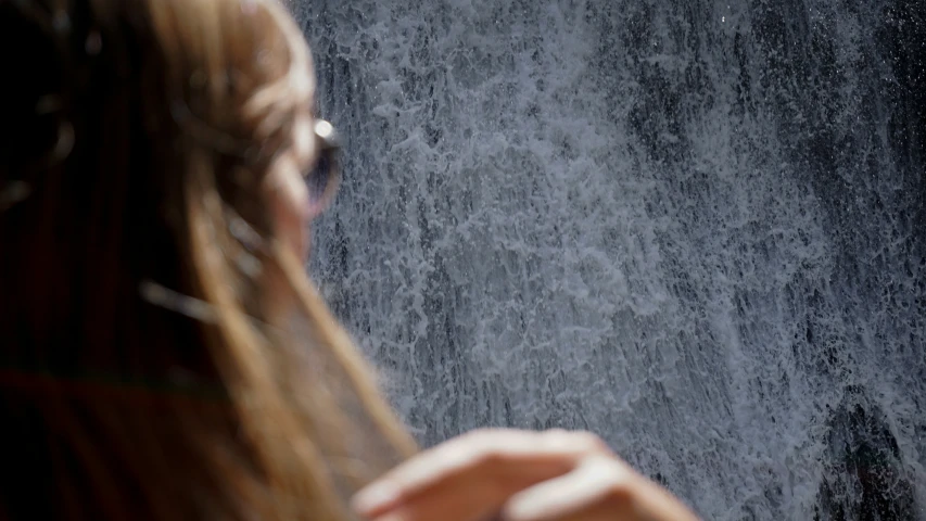 woman's face is covered by the rain that comes from behind her