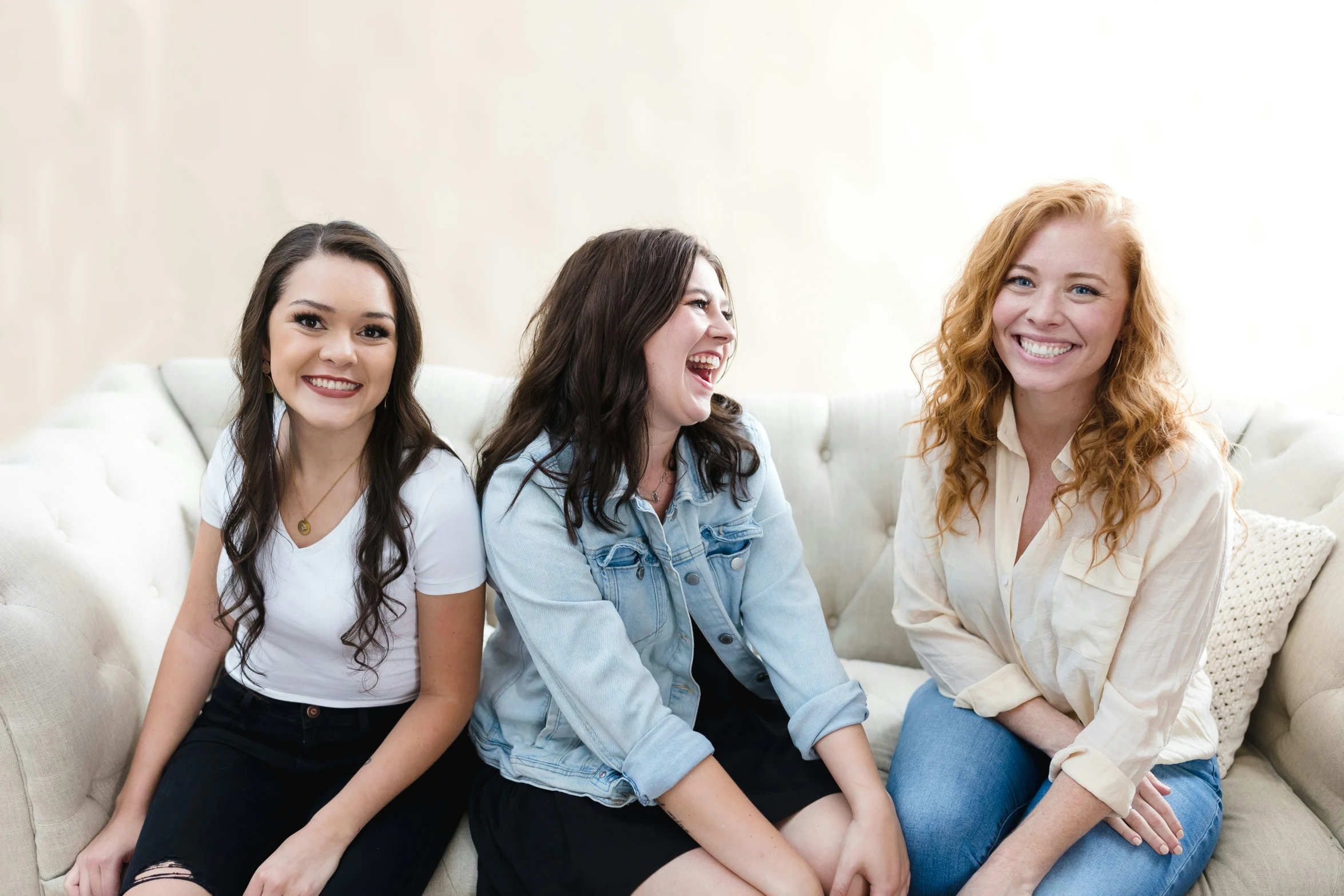 three girls laughing while sitting on a couch