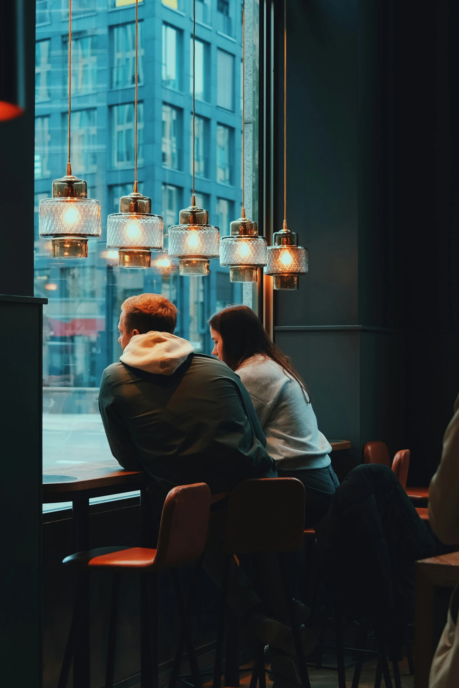 two people sitting at a restaurant table looking out a window