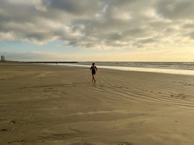 a woman is running along the beach towards the ocean