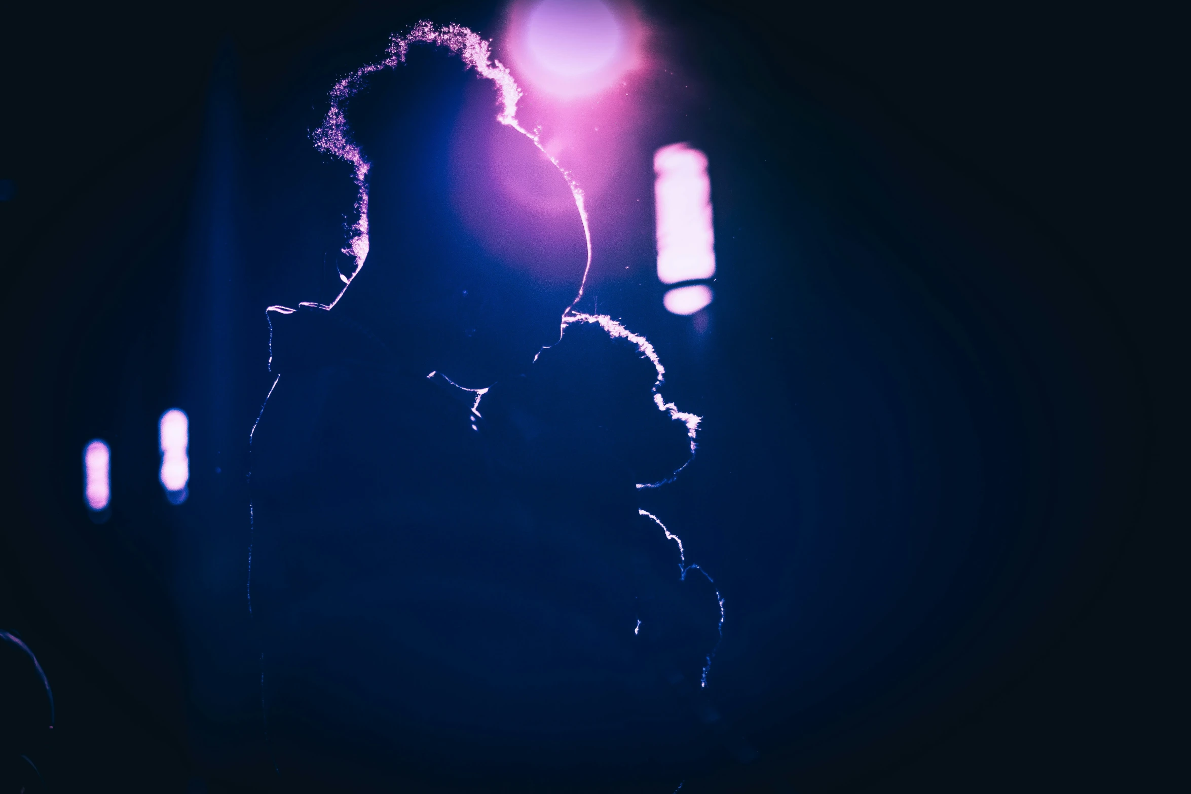 silhouettes of two people in front of spotlight