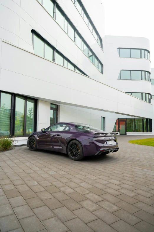 purple sports car in front of a large white building