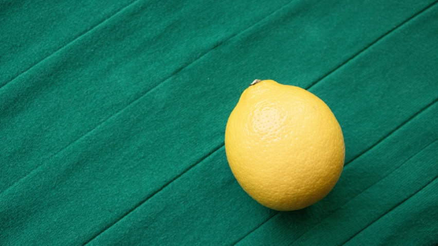a yellow lemon on a green background with a small object in the foreground
