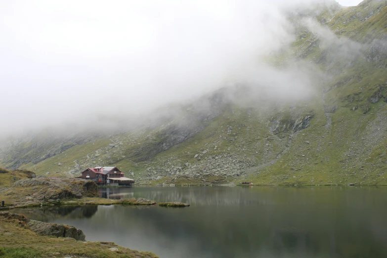 the house is surrounded by fog and low mountain ranges