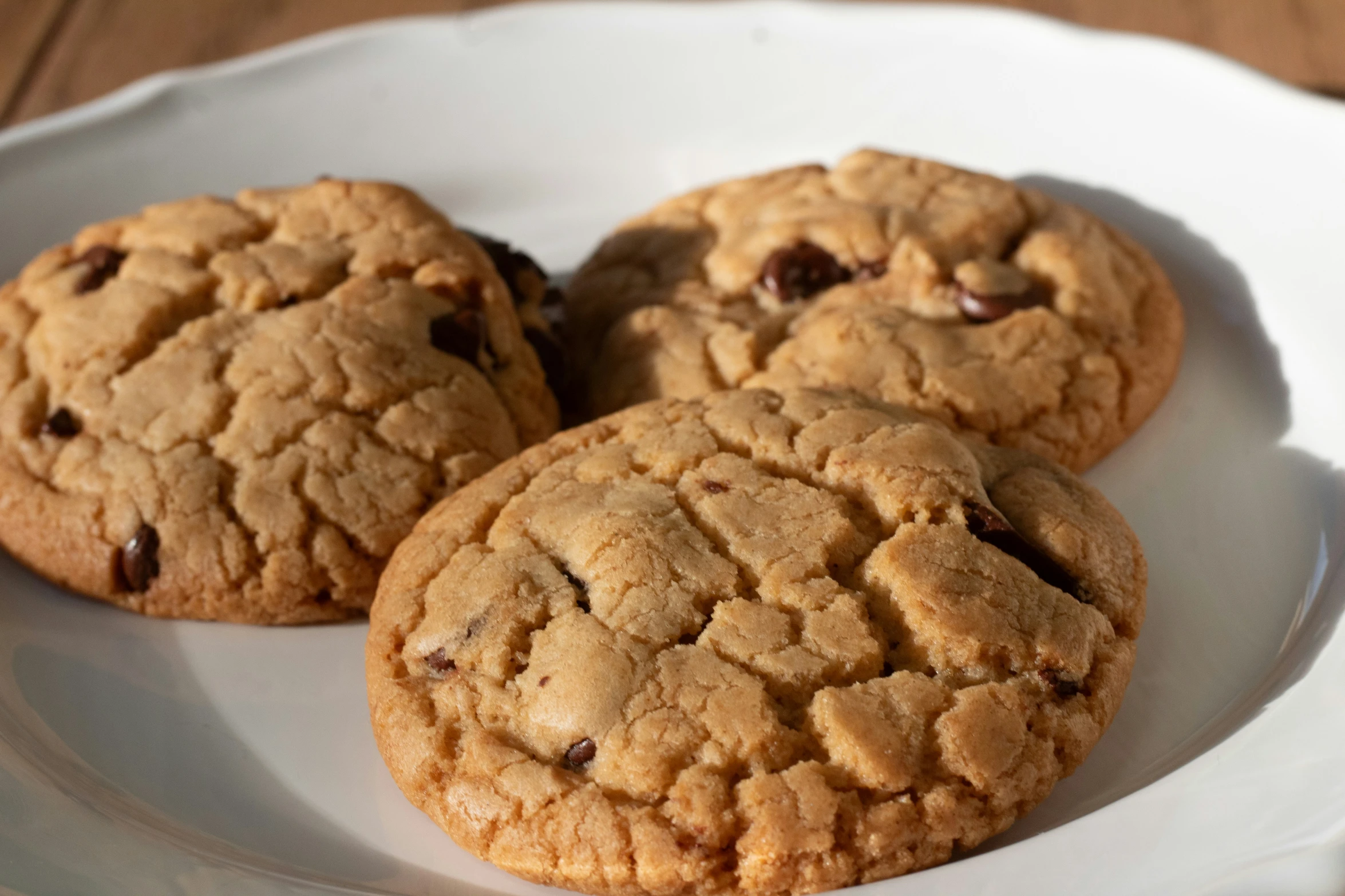 three chocolate chip cookies sitting on top of a white plate