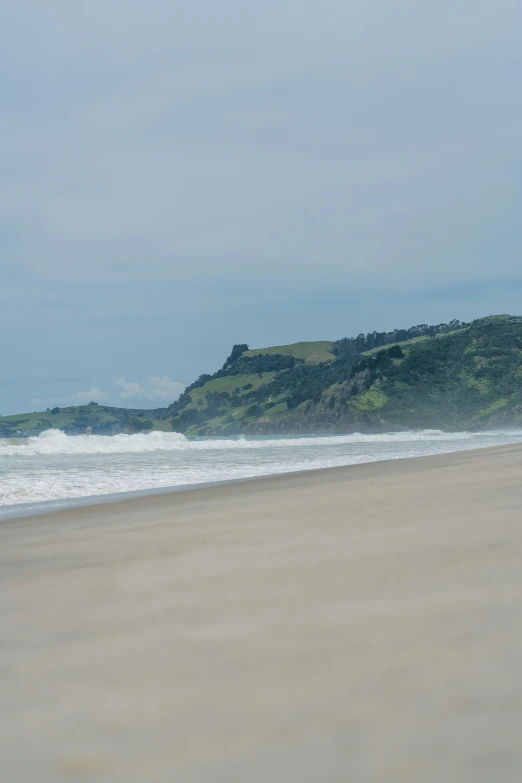 someone walks on the beach carrying a surfboard