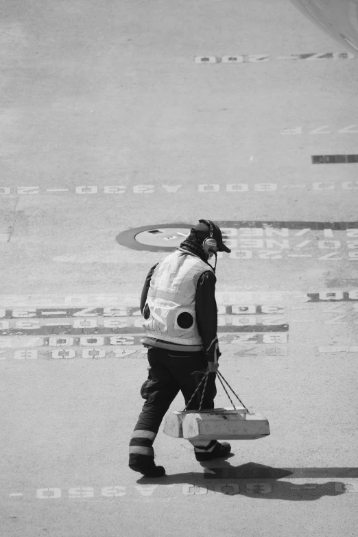 black and white pograph of man walking along airport pavement