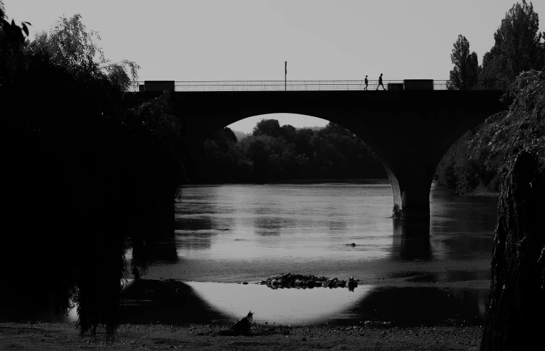 a black and white po of a bridge in the middle of a river