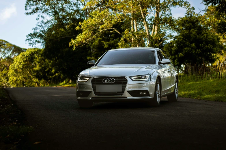 a silver car is driving on a road